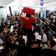 A passenger walks past protesters sitting on the floor in front of security gates during a demonstration at Hong Kong airport, Aug. 13, 2019.